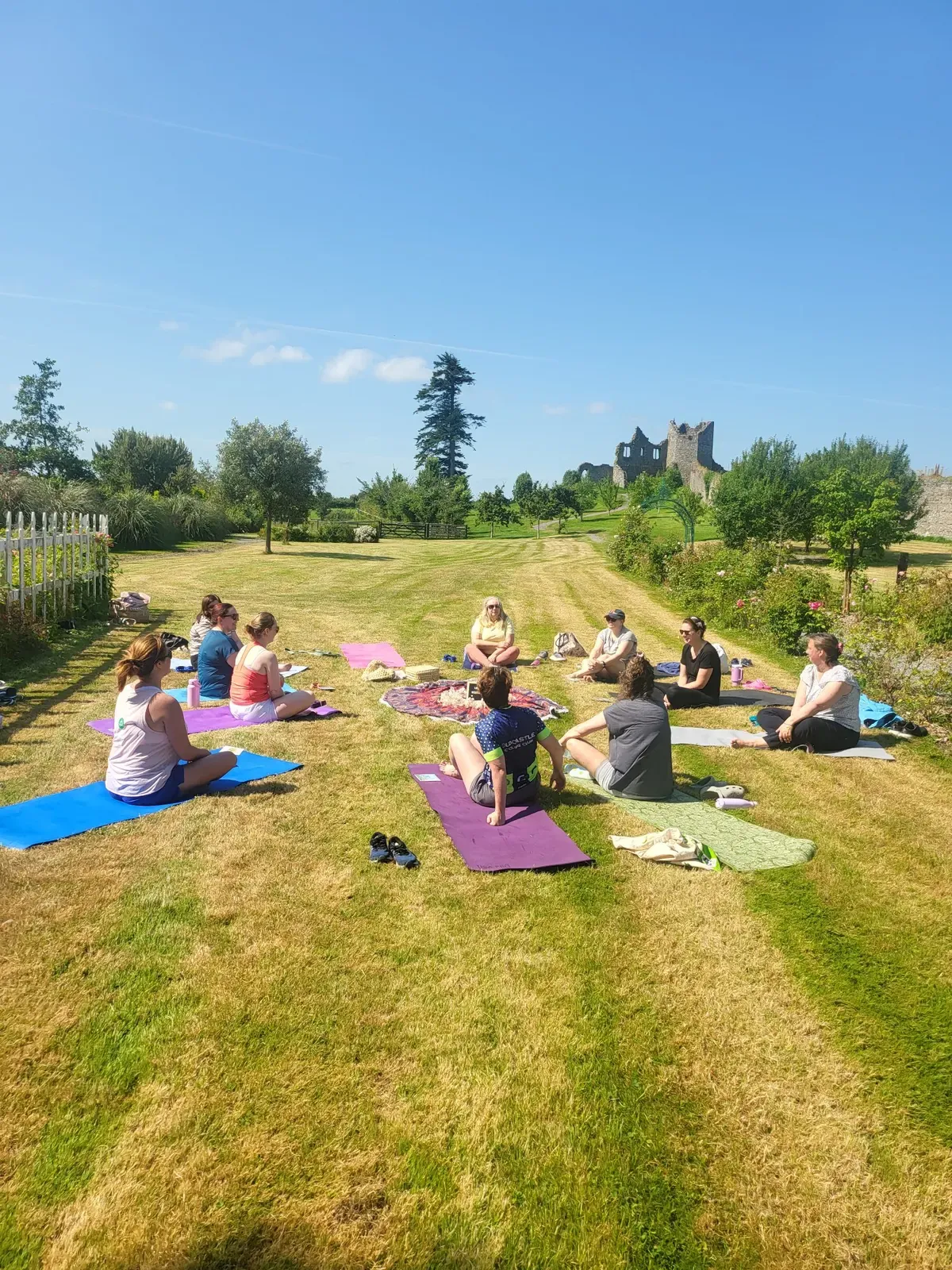 A small group sitting on yoga mats in a circle on the lawn at Killua Castle, near Athboy