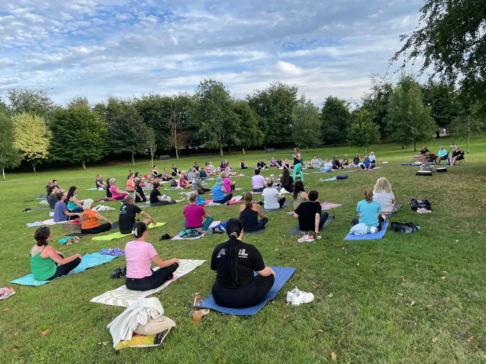 A big summer park yoga class, with mats spread across the grass